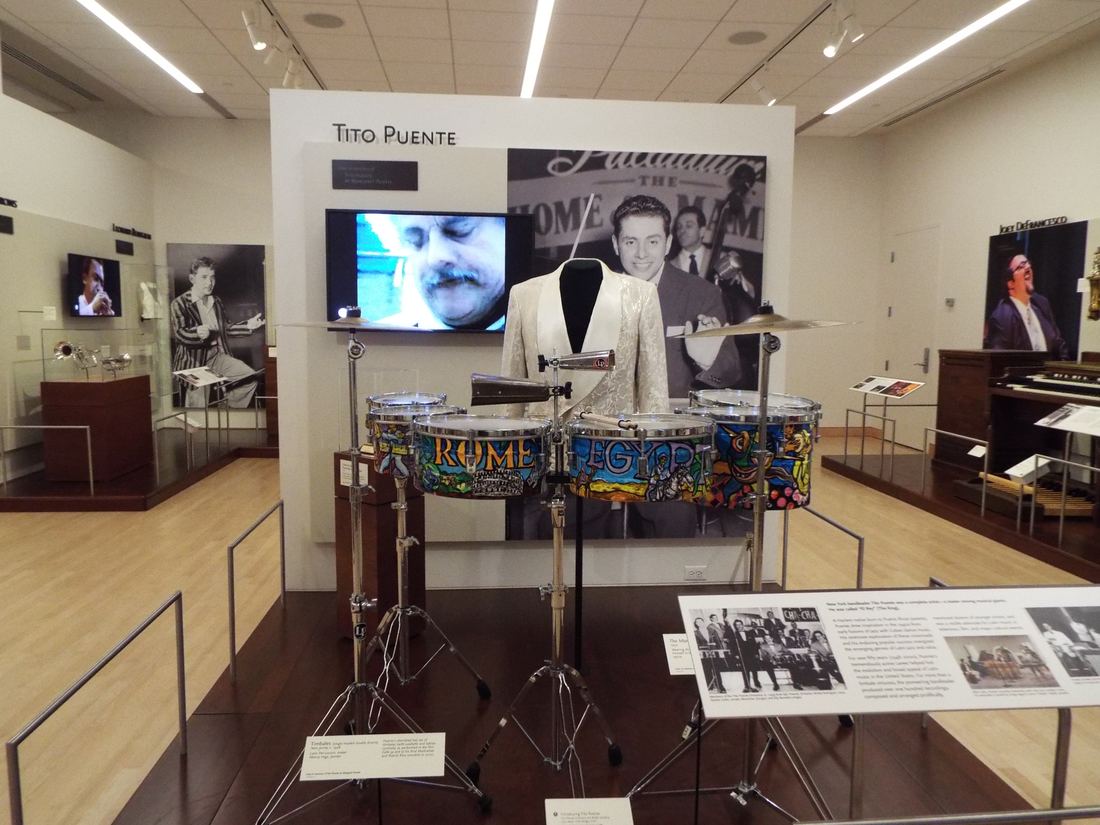 A museum exhibit with Tito Puente's timbales, stage outfit and photos